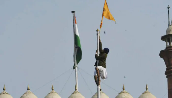 A protestor climbs atop the Red Fort to hoist a flag of their own
